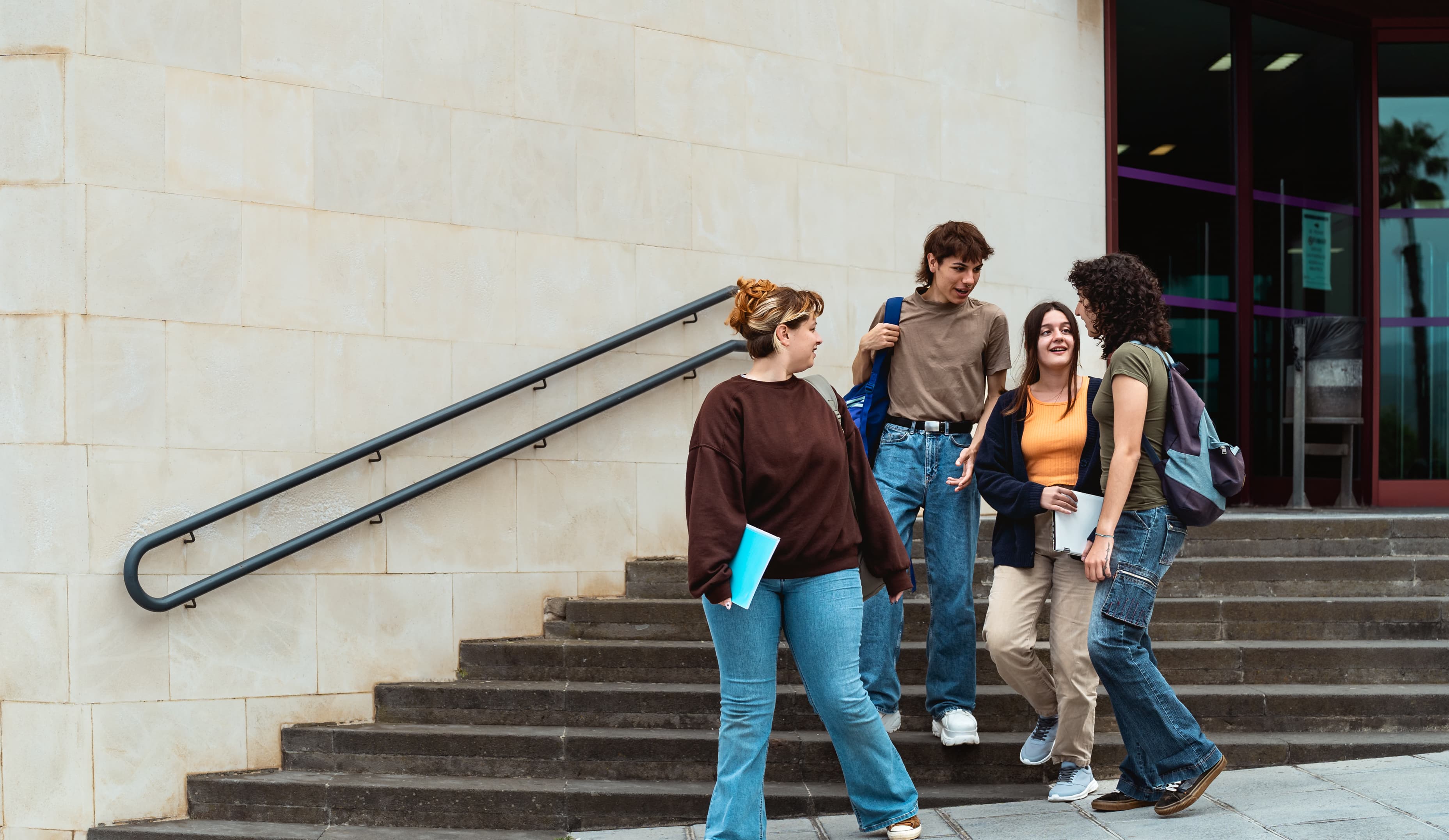 Group of four students walking across university campus