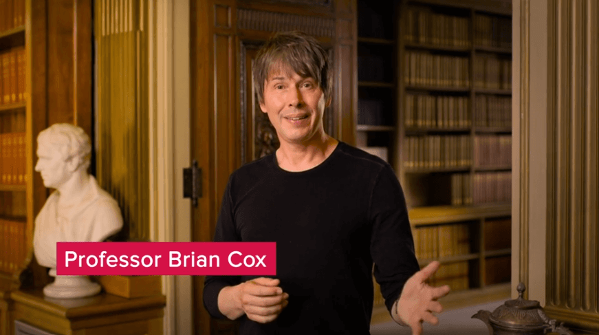 A screenshot of a man in a black sweater stood in an elaborate old-fashioned library. A title banner over the video says 'Professor Brian Cox'