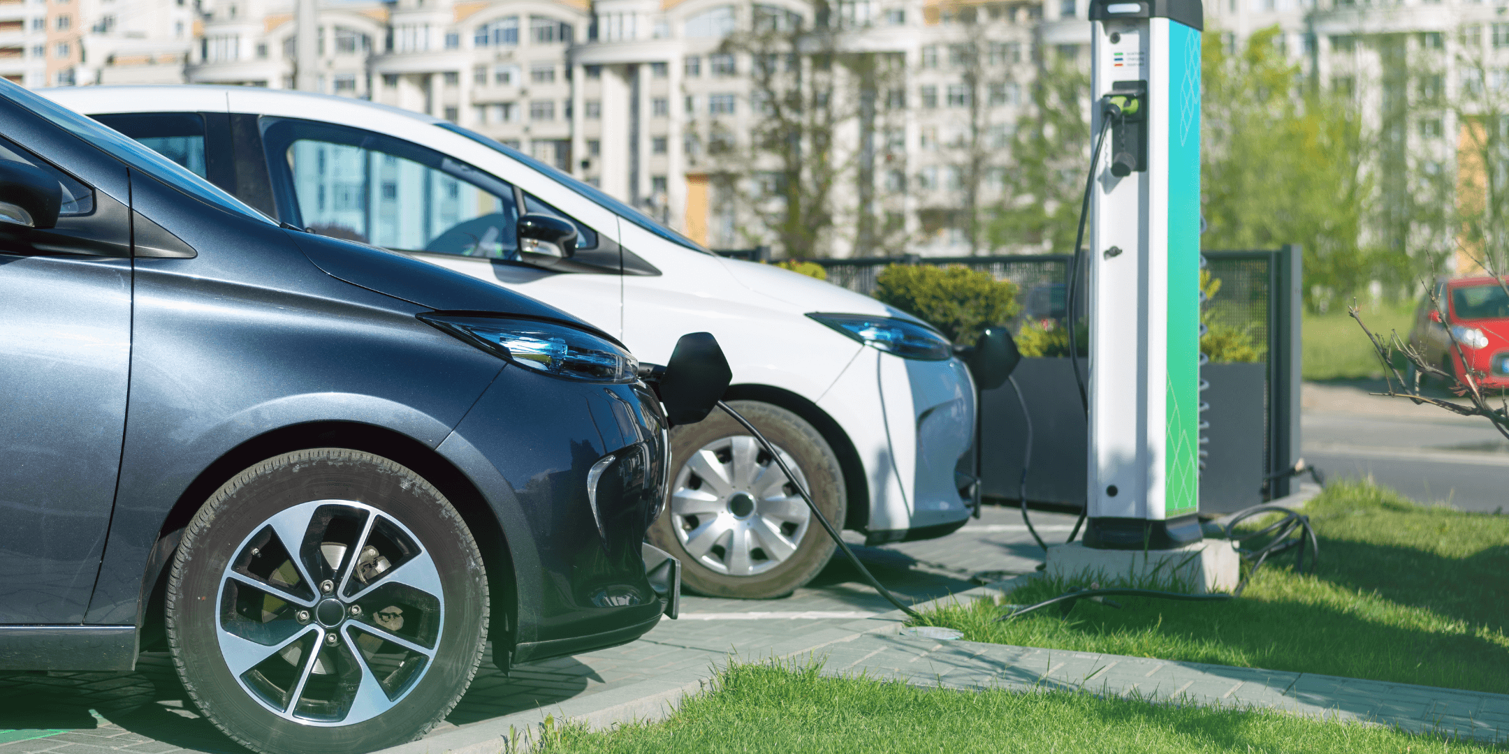 Two electric cars charging at a charging station.
